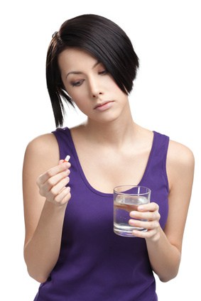 Woman with glass of water takes pills, isolated on white. Taking medication